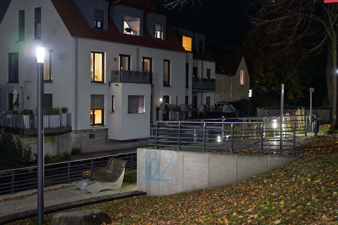 Buildings illuminated at night with autumn leaves on ground